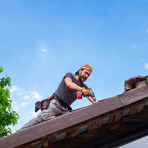 Man working on roof using electric screwdriver